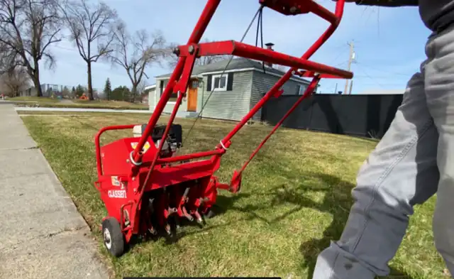 A red core aerator working across a lawn