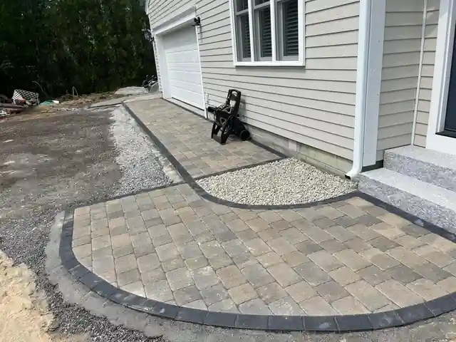 A new curved paver walkway with a charcoal border along the side of a garage