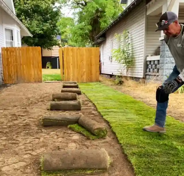 Rolls of sod being laid along a side yard